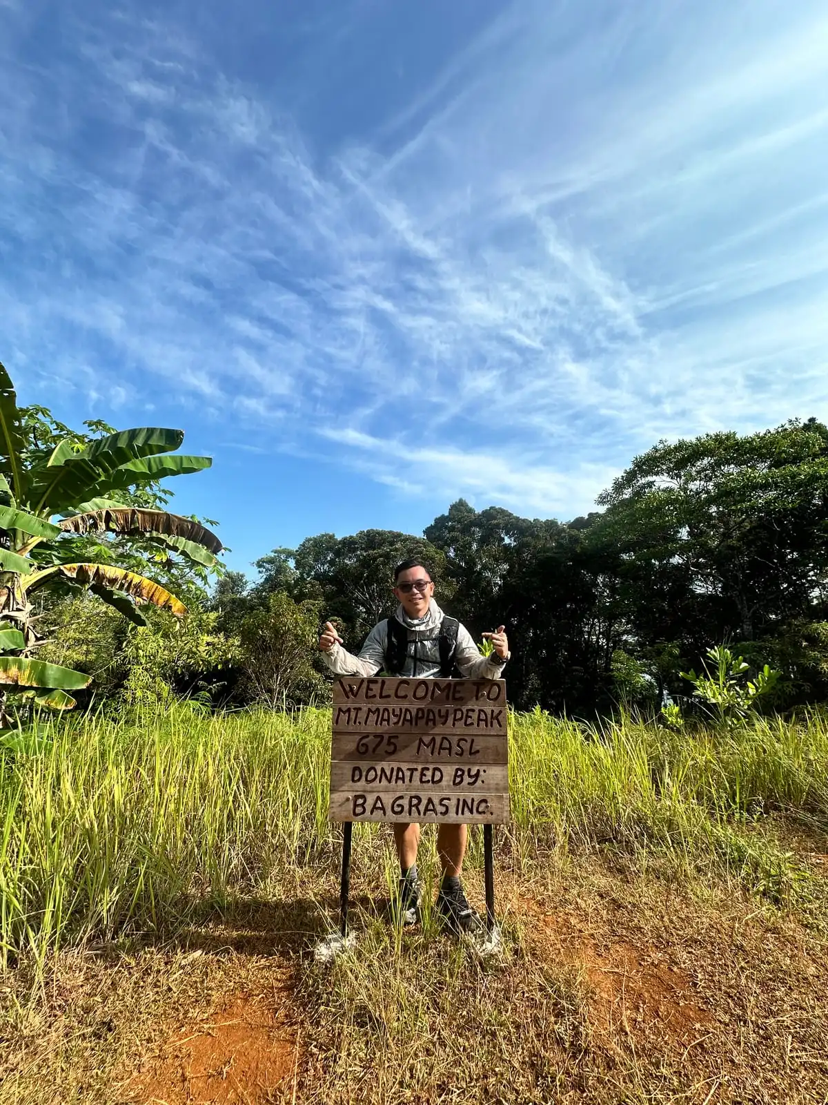 Standing behind the wooden welcome sign at the Mt. Mayapay peak, 675 metres above sea level