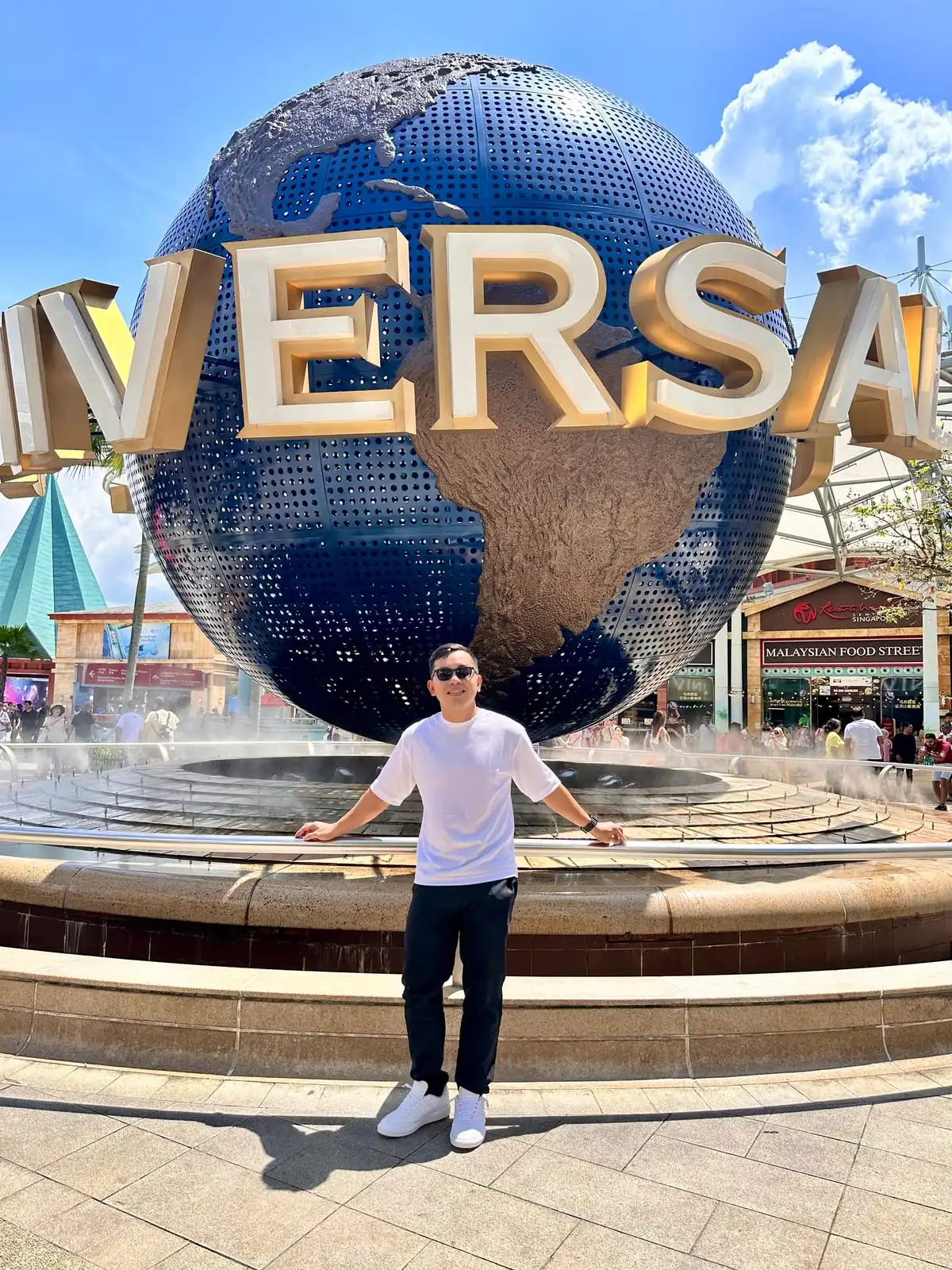 Standing in front of the giant globe at Universal Studios Singapore on a sunny day